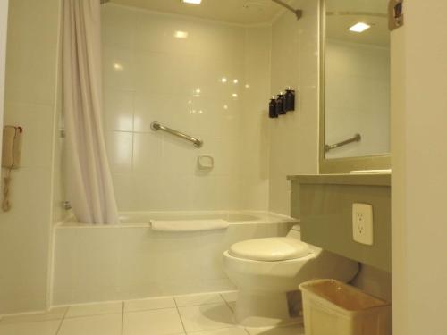 a white bathroom with a toilet and a shower at Mercure Alameda Quito in Quito