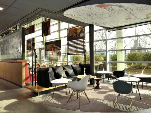 a lobby with tables and chairs in a building at ibis Amsterdam City West in Amsterdam