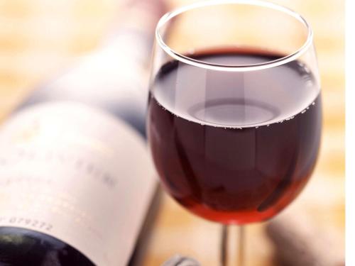 a glass of red wine next to a bottle of wine at ibis Amsterdam City West in Amsterdam