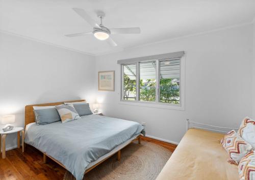 a white bedroom with a bed and a window at Sea Dip at Iluka in Iluka