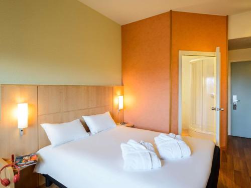 a bedroom with a large white bed with two towels at Hotel Ibis Milano Malpensa in Cardano al Campo