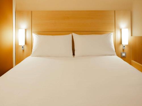 a large white bed with two pillows in a hotel room at Hotel Ibis Milano Malpensa in Cardano al Campo