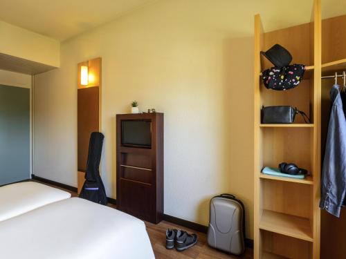 a hotel room with a bed and a tv at Hotel Ibis Milano Malpensa in Cardano al Campo