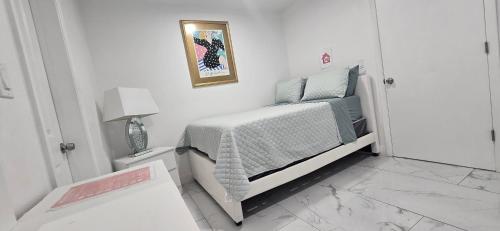 a small white bedroom with a bed and a lamp at Araly's house in Tampa