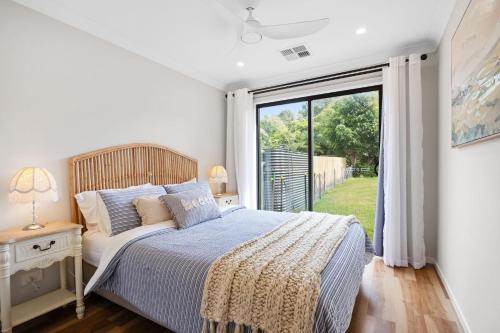 a bedroom with a bed and a large window at Ahgunyah Beach House in Mollymook