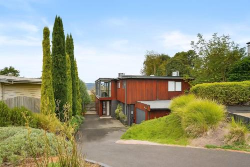 a red house in a garden with trees at Nature Comfort Views Dromana Family Retreat in Dromana