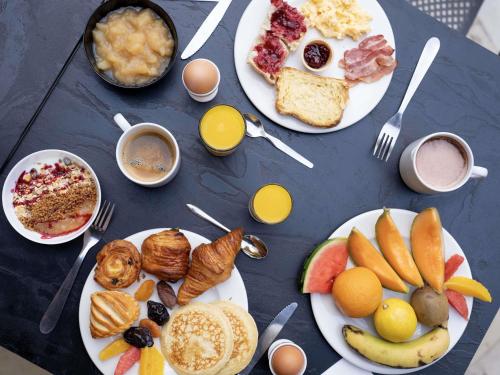 a blue table with plates of breakfast food on it at Ibis Styles Cognac in Châteaubernard
