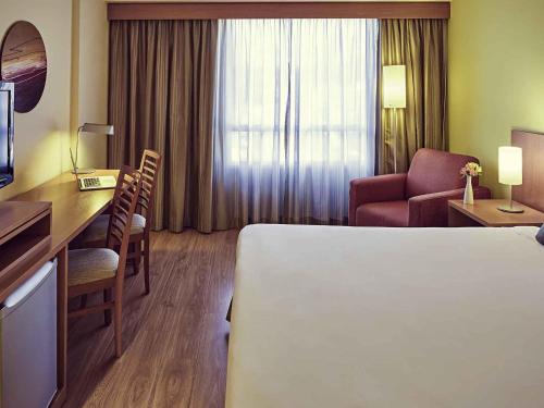 a hotel room with a bed and a desk at Mercure Sao Jose dos Campos in São José dos Campos