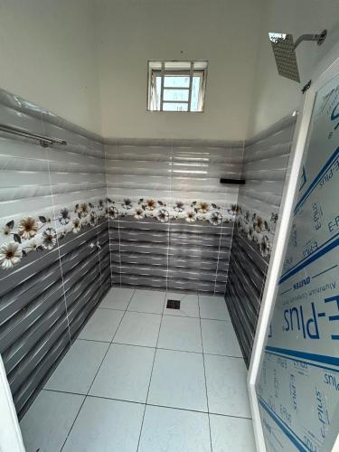 a walk in shower with gray walls and white tiles at Dviewhomestay in Jitra