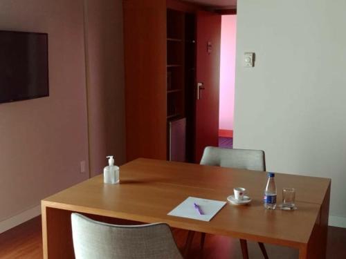 a wooden table with two chairs and a bottle and a paper at Mercure Campinas in Campinas