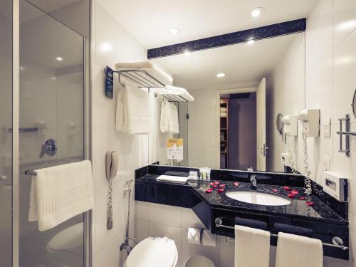 a bathroom with a sink and a toilet and a mirror at Mercure Campinas in Campinas