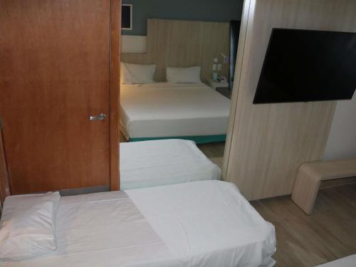 a hotel room with two beds and a television at Mercure Salvador Rio Vermelho in Salvador