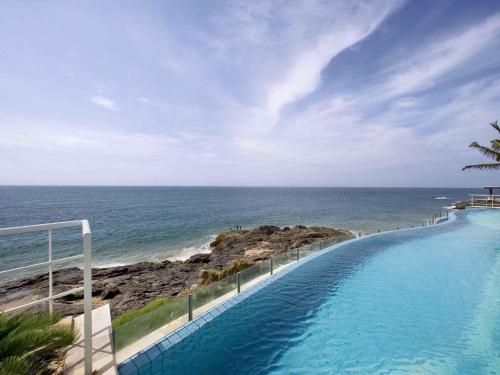 a swimming pool with a view of the ocean at Mercure Salvador Rio Vermelho in Salvador