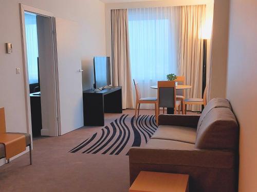 a living room with a couch and a tv and a table at Novotel Vilnius Centre in Vilnius