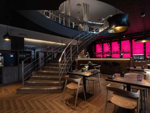 a staircase in a restaurant with tables and chairs at Novotel Vilnius Centre in Vilnius