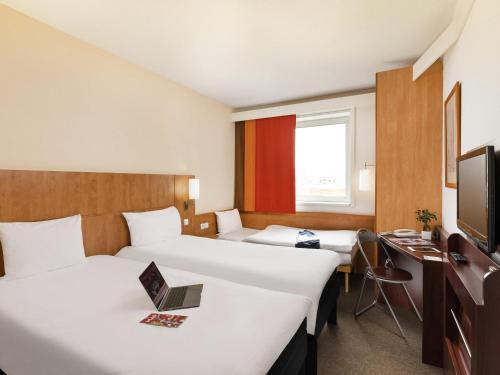 a hotel room with two beds and a television at Ibis Praha Mala Strana in Prague