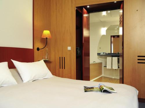 a bedroom with a bed with a book on it at Novotel Suites München Parkstadt Schwabing in Munich
