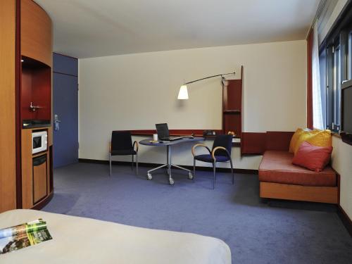 a room with a table with a laptop and chairs at Novotel Suites München Parkstadt Schwabing in Munich