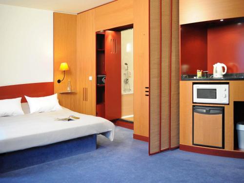 a hotel room with a bed and a kitchen at Novotel Suites München Parkstadt Schwabing in Munich