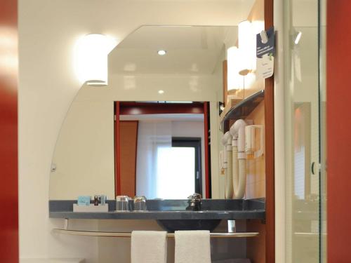 a bathroom with a sink and a mirror at Novotel Suites München Parkstadt Schwabing in Munich
