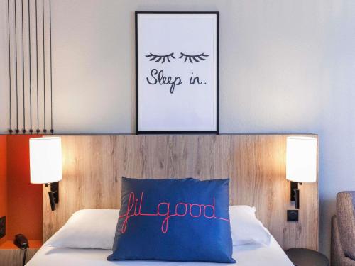 a bedroom with a bed with a blue pillow at ibis Styles Toulouse Lavaur in Lavaur
