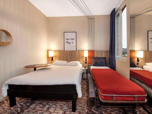 a hotel room with two beds and a red bench at ibis Styles Toulouse Lavaur in Lavaur