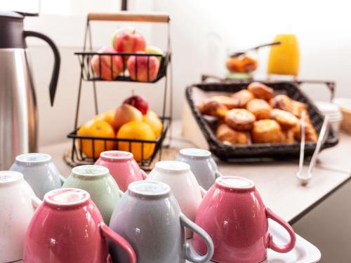 a group of pink vases on a counter with fruit at ibis Styles Toulouse Lavaur in Lavaur