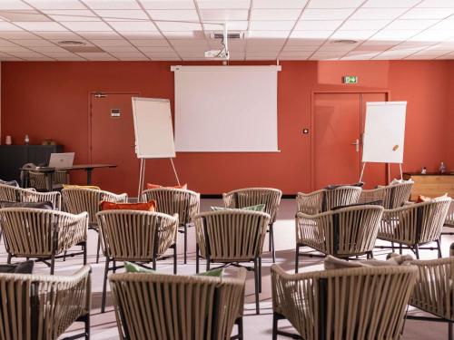 an empty room with chairs and a white screen at ibis Styles Toulouse Lavaur in Lavaur