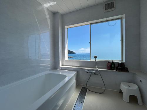 a white bathroom with a large tub and a window at 貸別荘 波音と朝日 namine to ASAHI in Miyazu
