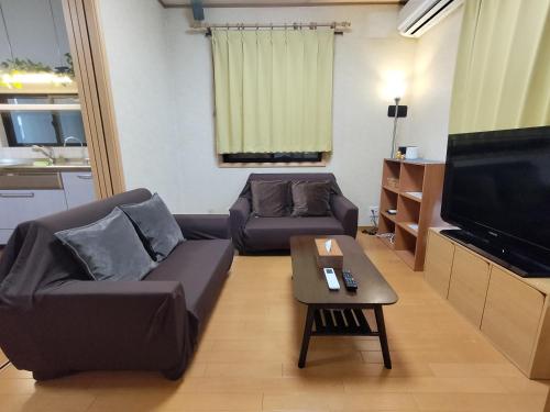Una sala de estar con un sofá y un televisor. en Lucky Higashimizue ラッキー東瑞江, en Tokio