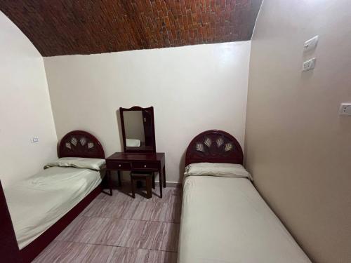 two beds in a room with a mirror and a table at Hamd Nubian Guest House in Aswan