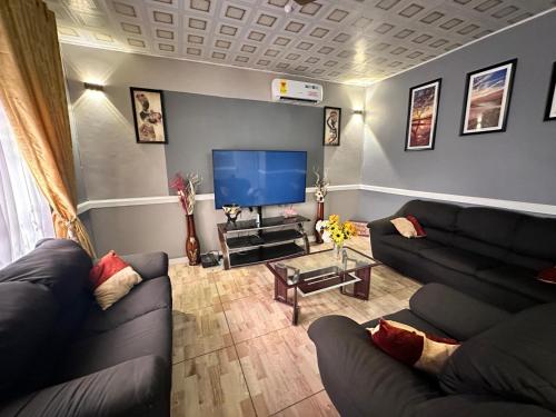 a living room with couches and a flat screen tv at Groove Vacation Homes in Kasoa
