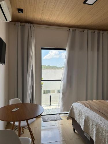 a bedroom with a bed and a table and a window at Pousada Bella Flor in Baía Formosa
