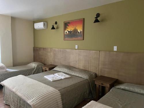 a room with two beds and a picture on the wall at Pousada Raio de Sol in Jaguarão