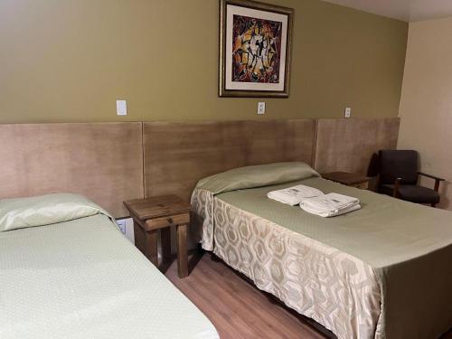 a hotel room with two beds and a chair at Pousada Raio de Sol in Jaguarão