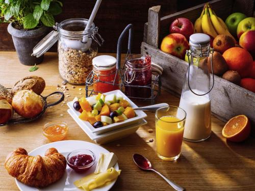 a table with a breakfast of fruit and juice at ibis München Parkstadt Schwabing in Munich