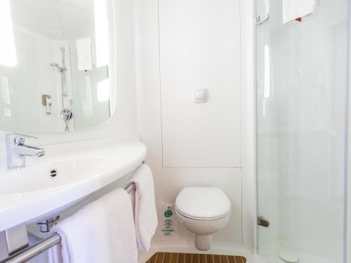 a white bathroom with a sink and a toilet at Ibis Elche in Elche