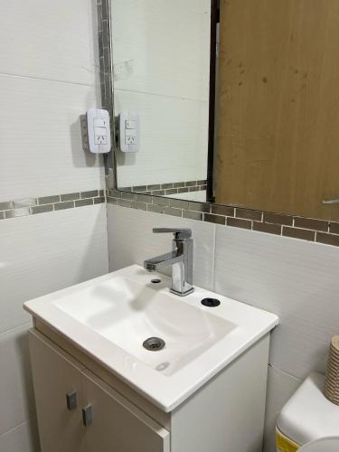 にあるLa MERCEDの白い洗面台と鏡のあるバスルーム