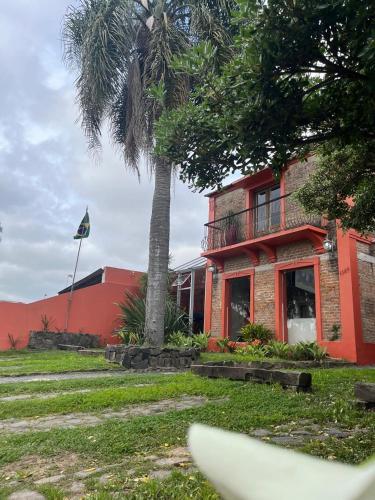 a red building with a palm tree in front of it at Pousada Raio de Sol in Jaguarão
