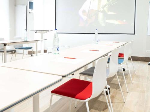 a conference room with white tables and red chairs at Ibis Elche in Elche