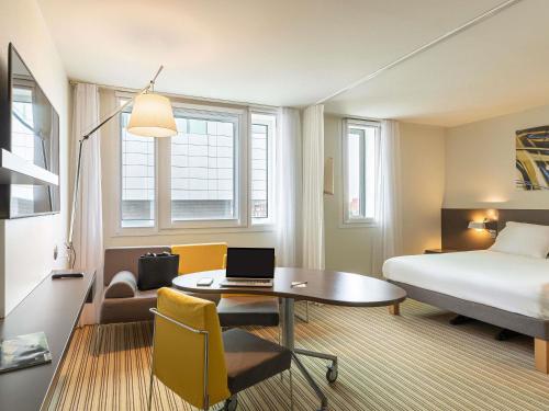 a hotel room with a bed and a desk with a laptop at Novotel Suites Lille Europe in Lille
