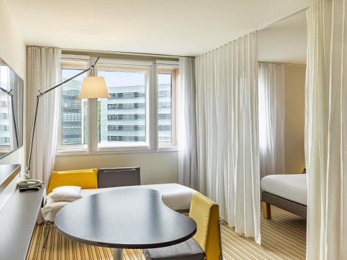 a hotel room with a table and a bed at Novotel Suites Lille Europe in Lille