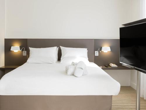 a large white bed with two teddy bears on it at Novotel Suites Lille Europe in Lille