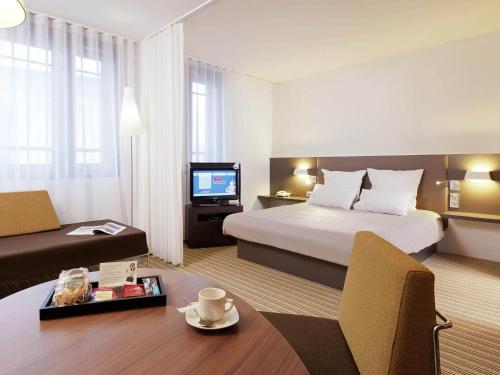 a hotel room with a bed and a television at Novotel Suites Lille Europe in Lille