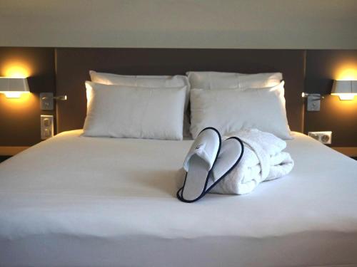 a white bed with towels and a computer mouse on it at Novotel Suites Lille Europe in Lille