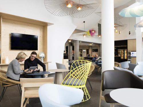 two people sitting at a table in a restaurant at Novotel Suites Lille Europe in Lille