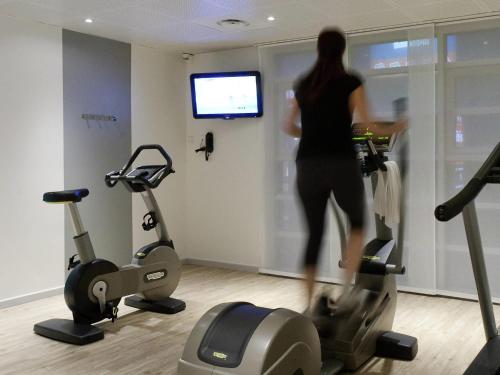 a woman in a gym with two exercise bikes at Novotel Suites Lille Europe in Lille