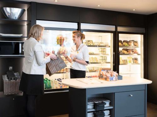 two women are standing in front of a refrigerator at Novotel Suites Lille Europe in Lille