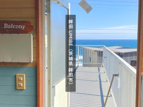 a building with a balcony with the ocean in the background at 海の見える高台に佇む隠れ家宿 #貸別荘 #一棟貸切 #グループや家族旅行におすすめ #テラスで海を眺めながらBBQ #雨天時や気温の低い日は屋内でBBQが楽しめるスペース有 #BBQグリル付 #大洗 #鉾田 #umibe in Hokota