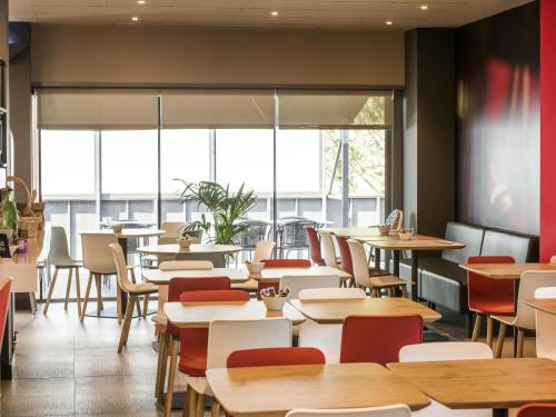 a restaurant with tables and chairs and large windows at Ibis Montmelo Granollers in Granollers